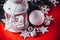 Magical white lantern is standing with white knit star on it and a fir tree branch and a snowball on a christmas red background.