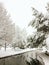 Magical winter landscape in a park with a pond and garden swings covered with the first fluffy snow