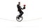 Magician with a wand riding a unicycle and performing a trick with red roses and a hat