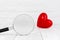 Magifying glass with red heart shaped on white background, find love concept