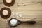 Magnesium Chloride Flakes scattered around brown wooden spoon on natural wood background.