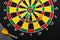 Magnetic dart arrows on dartboard. Black background