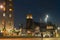 Magnificent clock tower building  of St. Lawrence Church in background of city square illuminated at night with blurred figure of