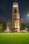 Magnificent entrance and clock tower on St. Lawrence Church illuminated at night across bright green lawn in vertical composition