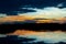 Magnificent evening sky over lake in Botswana with dark and orange clouds, bright blue sky and reflections in water at sunset.