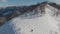 Magnificent panoramic shot of peaks covered in snow. Person with snowboard walking to unusual place to ride. Aerial view