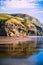 Magnificent rock formations reflected in gentle tidal waves running over the shore.