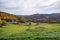 Magnificent rolling rural landscape with a farm at the foot of a wooded hill at the peak of fall foliage colours