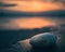 Magnificent sunrise on the beach with isolated pebble in the foreground