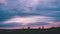 A magnificent sunset over a field with pink hues on the clouds