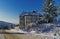 Magnificent winter landscape with a two-storey villa in the foreground and a rolling road going for a turn to the