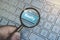 Magnified blue button Realty viewed through loupe on keyboard background. Concept of internet property seaching services