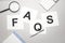 magnifier,calculator, pen and paper sheet with text faqs