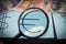 Magnifier focused on the Euro sign, on a background of euro, dollar, reminbi banknotes