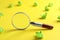Magnifier glass and green crumpled paper sheets on yellow background. Find keywords concept