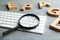 Magnifier glass, keyboard and letters on grey wooden table, closeup. Find keywords concept