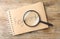 Magnifier glass and notebook with text KEYWORDS on wooden background