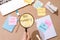 Magnifier glass and sticky note written new year goal word on wooden table