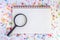 Magnifying glass on blank notebook with alphabet letter beads ba