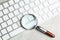 Magnifying glass and computer keyboard on grey marble table, top view. Search concept