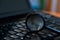 Magnifying glass on dusty dirty laptop keyboard in a dark room