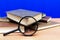 Magnifying glass a few closed books on a brown table blue background