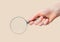 Magnifying glass lens magnifier in female hand closeup over natural beige background