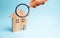 Magnifying glass is looking at the Wooden house on a blue background. The concept of affordable housing and mortgages to buy a