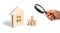 Magnifying glass is looking at the young family with children is standing near a wooden house. concept of a strong family,