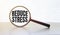 Magnifying glass with text REDUCE STRESS on wooden table