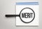 Magnifying glass with the word merit on chart background