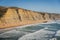 Magoito beach with surfers surfing on the sea waves in Sintra, Portugal