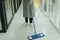 Maid using mop cleaning the floor in condo apartment room