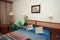 Maid woman, dressed in green, putting pillows on bed