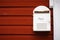 Mail box, post box on wooden red house wall background. Postal service in small village. White, rusty metal, rural postage box
