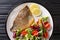 Main dish fried dorada fillet with vegetable salad close-up on a plate. Horizontal top view