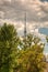 The main Moscow TV tower in Ostankino. Ostankino TV tower on the background of a summer storm sky through the green crowns of