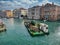 A maintenance barge carrying a supply of wooden pilings moves along a canal in central Venice, Italy on a cloudy day in Autumn