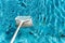 Maintenance man using a pool net leaf skimmer rake in summer to leave ready for bathing his pool