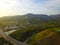 A majestic aerial shot of the lagoon along the mountain ranges with a freeway with cars driving and lush green trees and plants