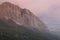 Majestic evening summer mountain landscape - high orange rocky ridge in soft mist in fluffy overcast weather and blue clouds