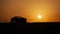 Majestic golden sunset over a silhouette of a car driving through a place lined with barbed wire