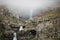 majestic icelandic landscape with waterfall on rocks in fog,