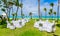 Majestic inviting gorgeous view of white fluffy pretty tables and chairs, prepared for a wedding ceremony in tropical garden