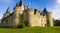 majestic medieval castle in the middle of a meadow by day