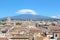 Majestic Mount Etna overlooking the Sicilian city Catania, Italy. Smoke cloud over the famous volcano, snow on the top. Dominant