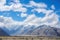 majestic mountain range with clear blue sky and fluffy clouds, seen from scenic road trip