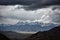 majestic mountain range, with clouds swirling and storms brewing in the distance