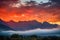 majestic mountain range in fiery sunset with clouds and mist
