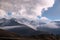 Majestic mountain view - rocky peaks covered with snow on the horizon with some dark brown autumn hills in front under the